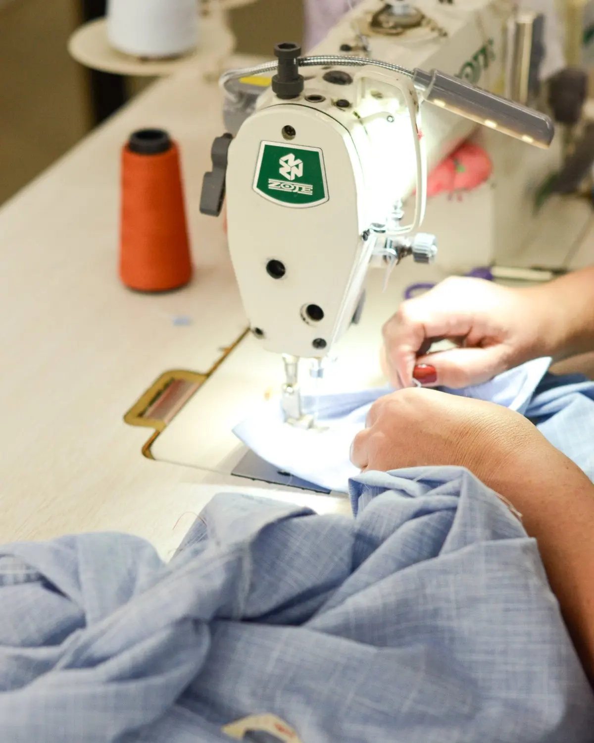Costureira trabalhando em uma peça na máquina de costura.