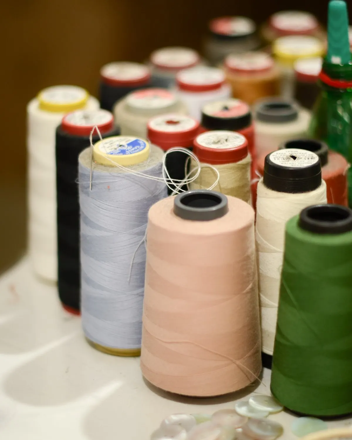 Cones de linha de costura em várias cores sobre a bancada.
